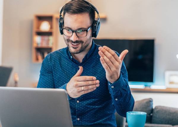 Ein Mann mit Headset, der vor einem Laptop sitzt und spricht.